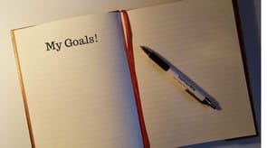 A notebook with the words'my goals'on it and a pen.
