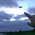 A person pointing at a flying object in the sky.