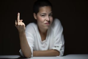 A woman pointing her finger at a dark table.